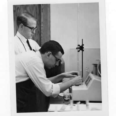 Two male students in shirt and ties conducting experiment in science laboratory.