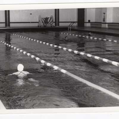 Students swimming in pool at sports recreation complex.