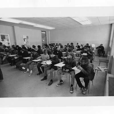 Children at Rhoads Public School (?) sitting in classroom. Part of student tutoring community service/outreach project. (Peace and Human Development program?)