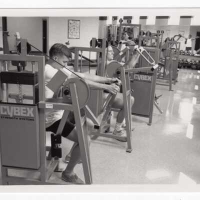 Men and women using exercise/fitness room in sports recreation complex.