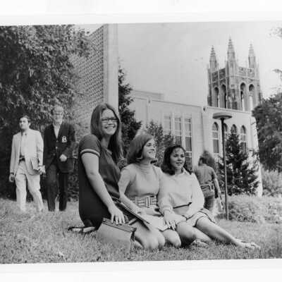 Women from first class of co-education sitting on lawn with Drexel Library in background.