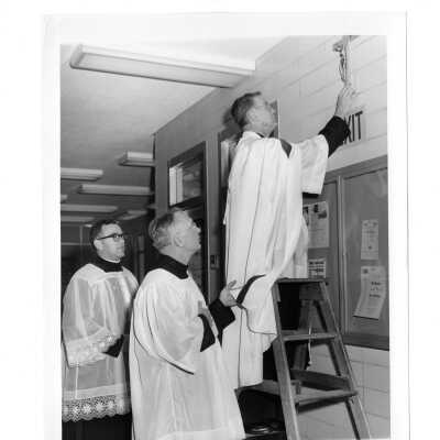 William F. Maloney, S.J. and others placing cross on wall of Drexel Library during dedication ceremony.