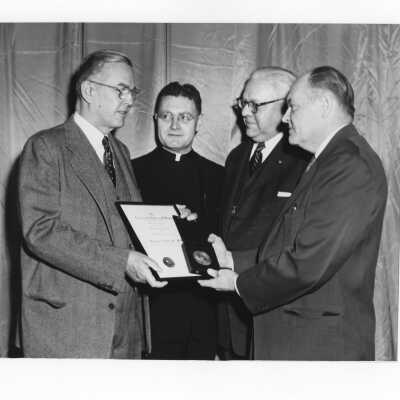 Dr. Joseph Stokes, Jr., showing Shaffrey award medal and certificate to Edward G. Jacklin, S.J., Dr. Myles J. Murphy, and Dr. Robertson in 1954.