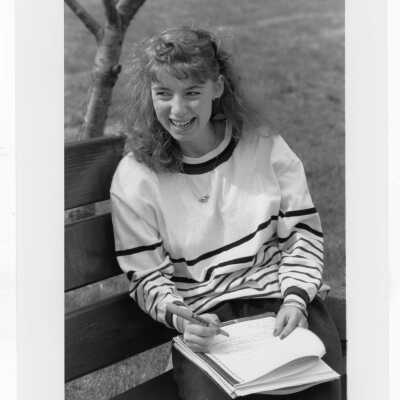 Female student sitting on bench outside.