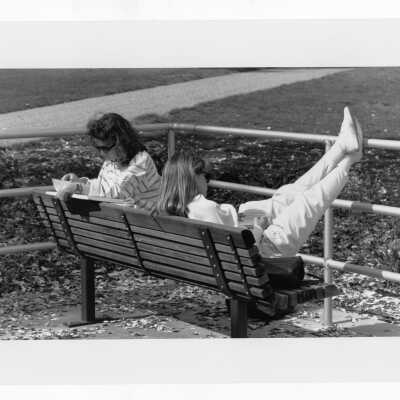 Two women students sitting on bench in front of Drexel Library.