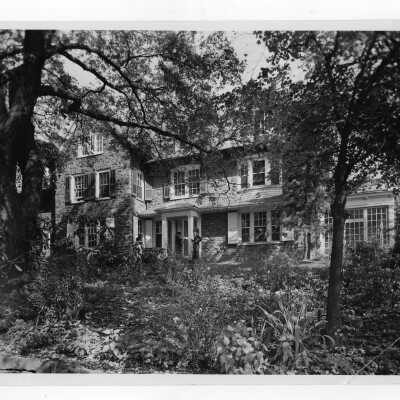 Exterior front view of Greaton Hall with three students standing and talking.