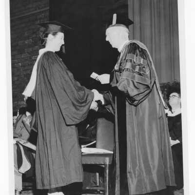 J. Joseph Bluett, S.J., congratulating a woman honors graduate from the Evening Division during 1958 graduation/commencement ceremony.
