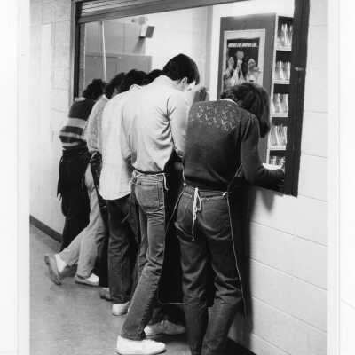 Students lined up at counter looking at paperwork during experiment in science laboratory.