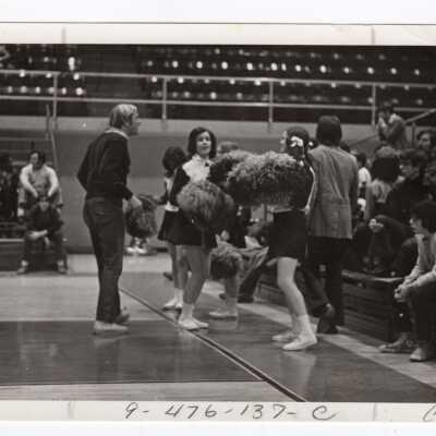 Women cheerleaders talking at basketball game.