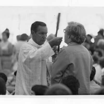Mass held July 31, 1976, on Gest Lawn prior to academic convocation during SJC 125th anniversary celebration. James Moore, S.J., distributing communion.