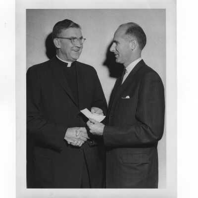 William F. Maloney, S.J., receiving fundraising check from alumni association officer, November 23, 1962.