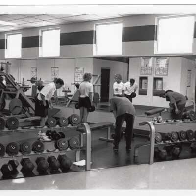 Men and women using exercise/fitness room in sports recreation complex.