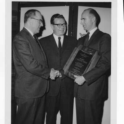 F. Frederick Perone holding Hogan Alumni Award plaque with John P. Clark and Governor Richard J. Hughes watching, February 12, 1964.