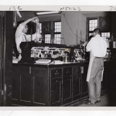 Two chemistry students working on experiment in science laboratory, c. 1965.