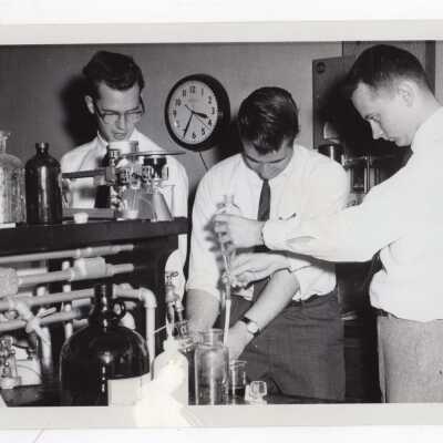Three chemistry students working on experiment in science laboratory, c. 1965.