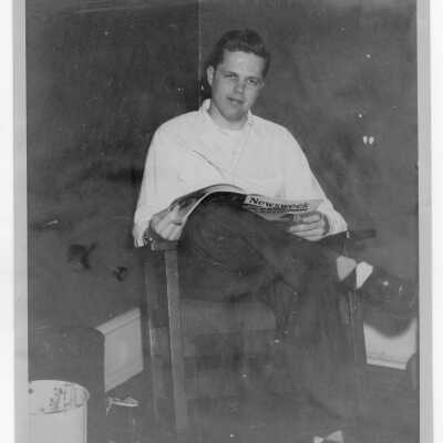Student from Barry Hall reading Newsweek magazine in dormitory room.