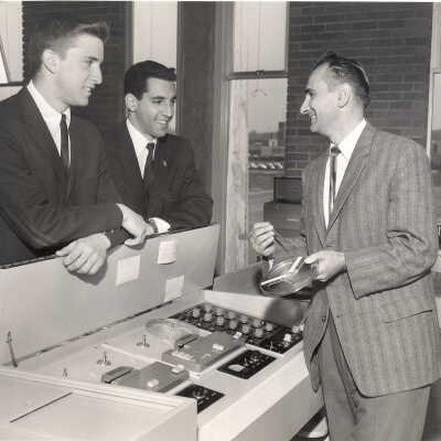 Modern Languages professor, Michael Toconita, and two students standing near tape recording machine in language laboratory.