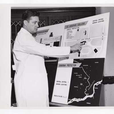 Chemistry professor, Joseph Feighan, pointing to charts indicating campus protection and suburban protection provided by Decker nuclear fallout monitor, April 17, 1962.