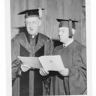 J. Joseph Bluett, S.J., looking at program with honorary degree recipient at October 1960 graduation/commencement.