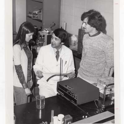 Biology professor, James Watrous, working with two students in science laboratory, March 1976.