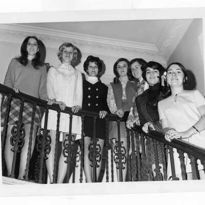 Several women students from first co-ed class standing on inside stairwell.