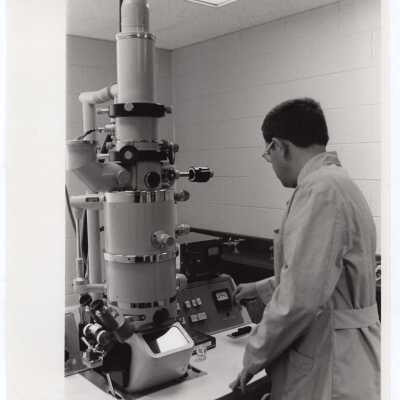 Biology professor, Frederick Monson, working with electron microscope, c. 1972.