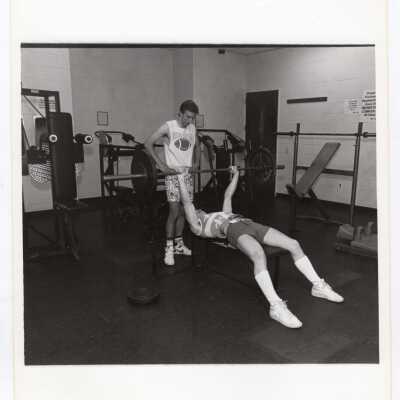 Men using lifting weights in exercise/fitness room in sports recreation complex.