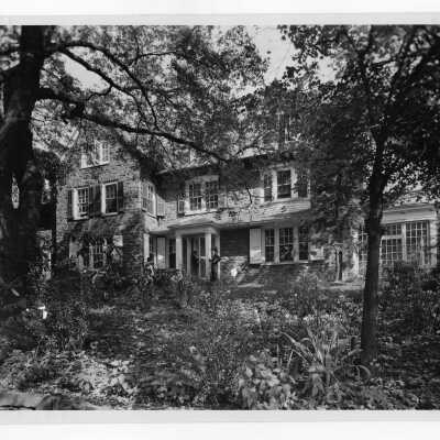 Exterior front view of Greaton Hall with three students standing and talking.