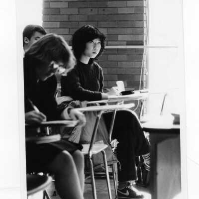 Several students sitting at desks in classroom listening to lecture.