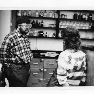 Two students talking in science laboratory during experiment.
