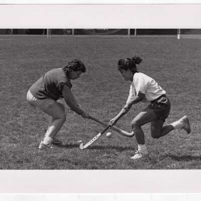 Two women practicing field hockey.