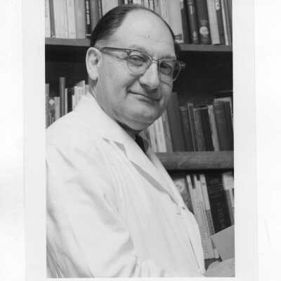 Louis S. Marks (Biology) wearing lab coat standing in front of bookcase; and Louis S. Marks in laboratory.