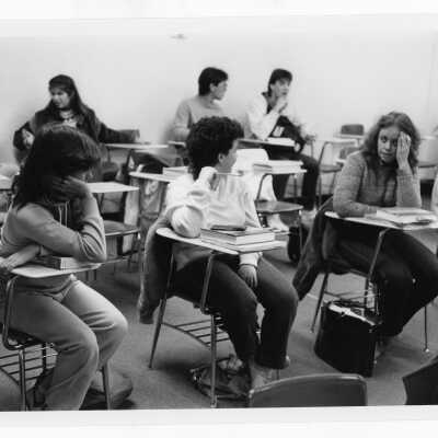 Students in classroom sitting at desks and talking.
