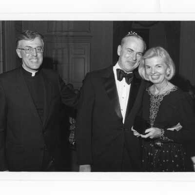Donald I. MacLean, S.J., presenting alumni award to Peter Byrne, with his wife, Nancy Brennan Byrne watching at alumni awards dinner, c. 1980.