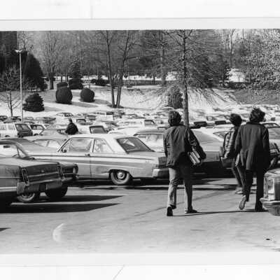 Parking lot near Barbelin with parked cars and students.