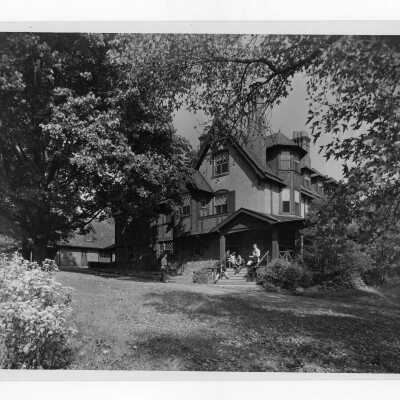 Exterior view of Simpson Hall with students on steps and porch.
