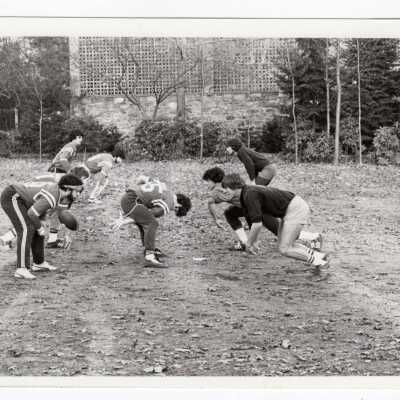 Men playing intramural football game on field near Gest estate?