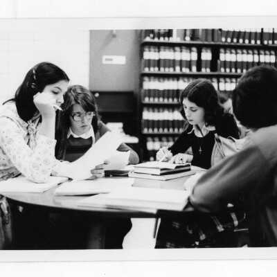 Women students studying at table in library.