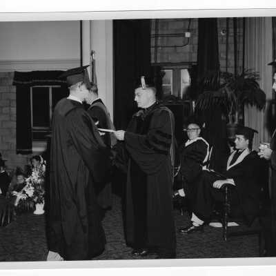 Tropaia exercises during 1955 graduation/commencement with Edward G. Jacklin, S.J. and student.