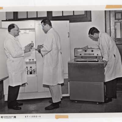 Biology professor, Louis Mark, working with two students in science laboratory, c. 1968.