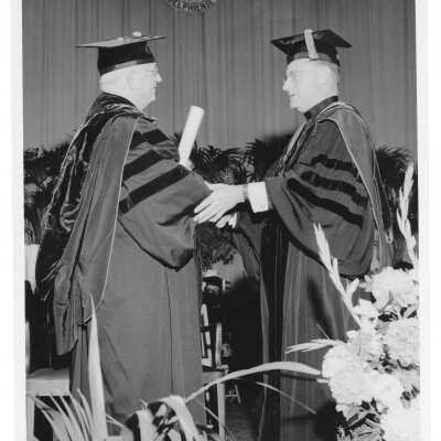 Edward G. Jacklin, S.J., congratulating honoree during 1956 graduation/commencement ceremony.