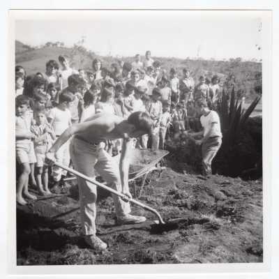 Two students working in field in Colombia with group of children watching during Latin American Studies Institute Summer Service Project, summer 1970.