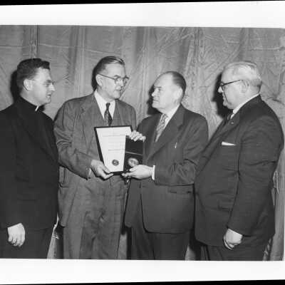Dr. Joseph Stokes, Jr., showing Shaffrey award medal and certificate to Edward G. Jacklin, S.J., Dr. Myles J. Murphy, and Dr. Robertson in 1954.