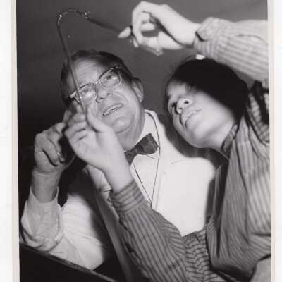 Chemistry professor with graduate student in science laboratory, c. 1960, possibly using glass blowing equipment.