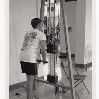 Man using weight machine in exercise/fitness room in sports recreation complex.