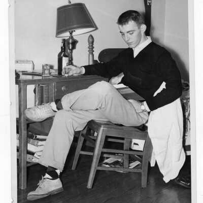 Student resident of Quirk Hall studying in room with bottle of liquor and Pall Mall cigarette pack.