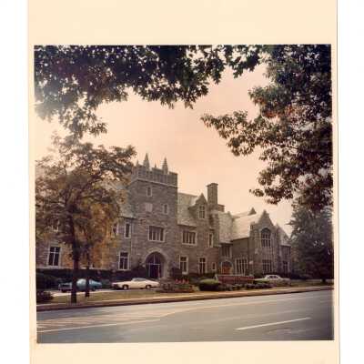 Exterior view of front of Barbelin building from City Avenue with three cars parked in driveway.