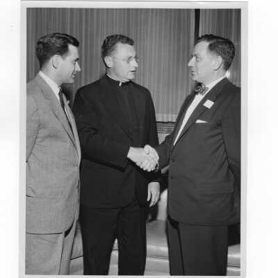 Edward G. Jacklin, S.J., and William Ariano congratulating newly elected alumni president, Francis Lammer, 1955.