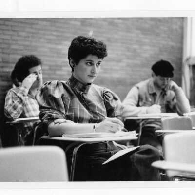Several students sitting at desks in classroom listening to lecture.