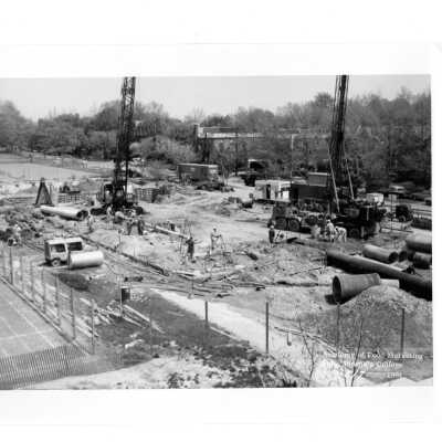 Early construction of Villiger (later Post) Academy of Food Marketing with workmen and equipment with tennis courts and neighborhood in background.